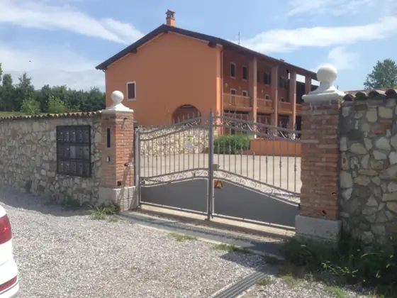 Cancello automatico a battente tra pilastri in mattoni all’ingresso di una villa